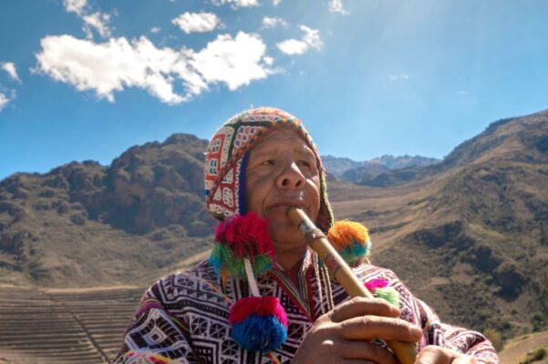 Senior man dressing traditional peruvian clothing and playing flute